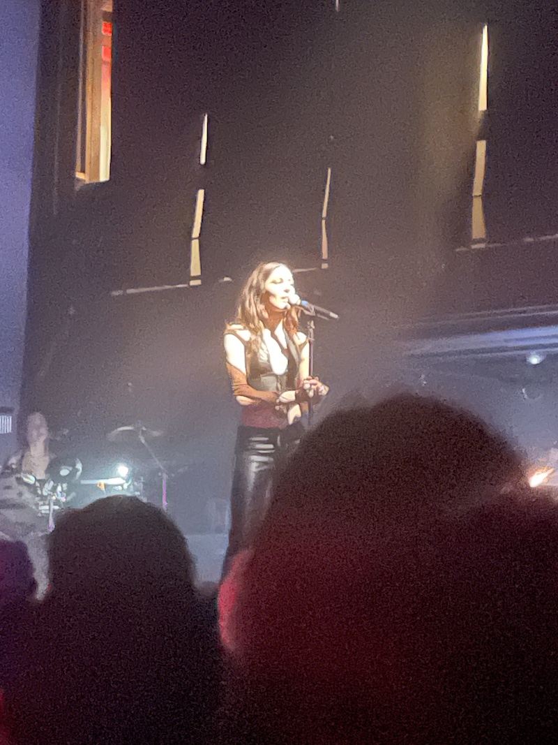 Caroline Polachek on stage, standing at a microphone